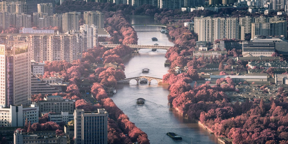 Gongchen Bridge over the Grand Canal, with waterfront buildings and trees in Hangzhou.