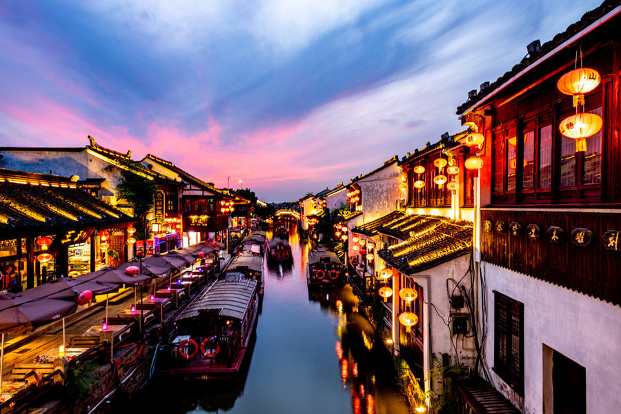Illuminated canal-side buildings along Shantang Street in Suzhou at night.