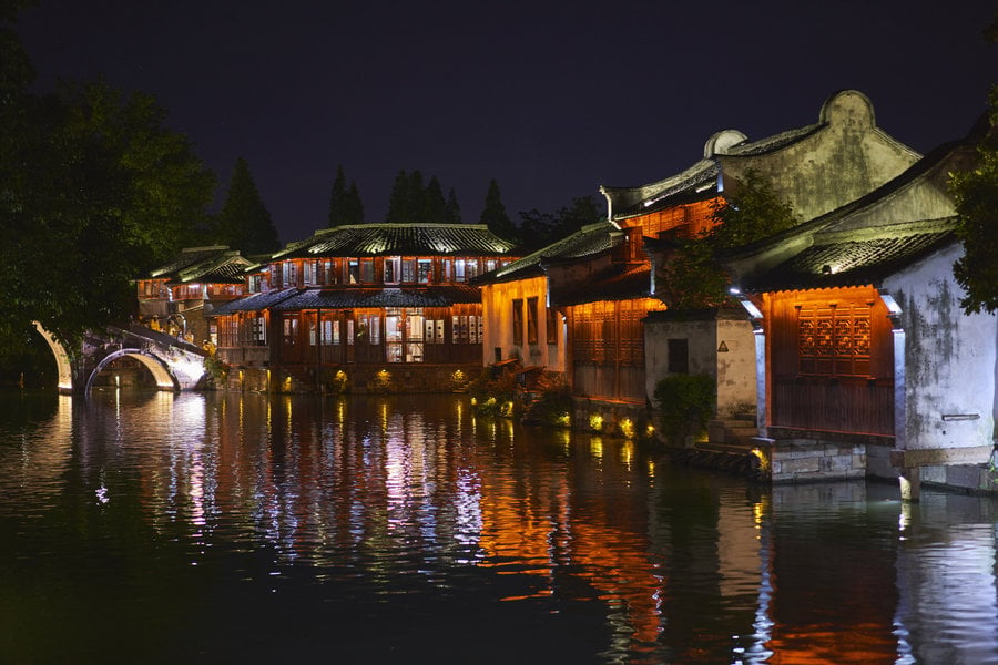 Illuminated waterside buildings reflected in a canal in Wuzhen
