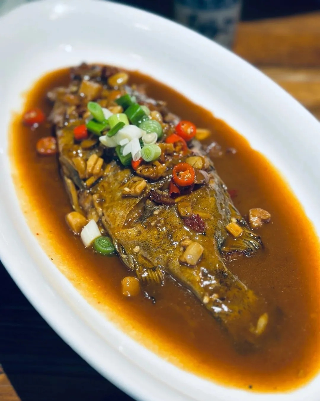 A whole fish in sauce topped with chillies and spring onions at Shui Mo Hui