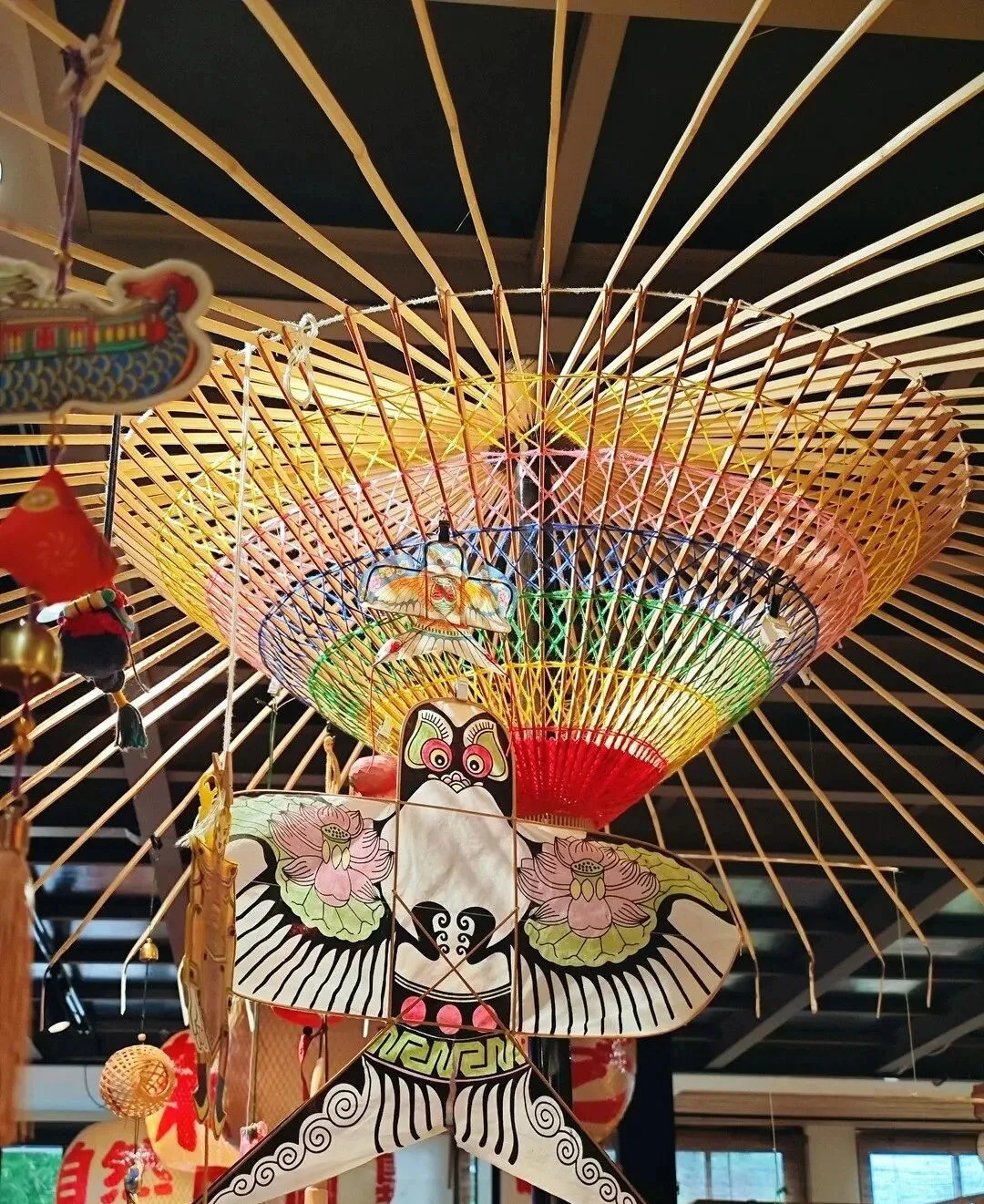 A colourful traditional kite displayed beneath a bamboo parasol